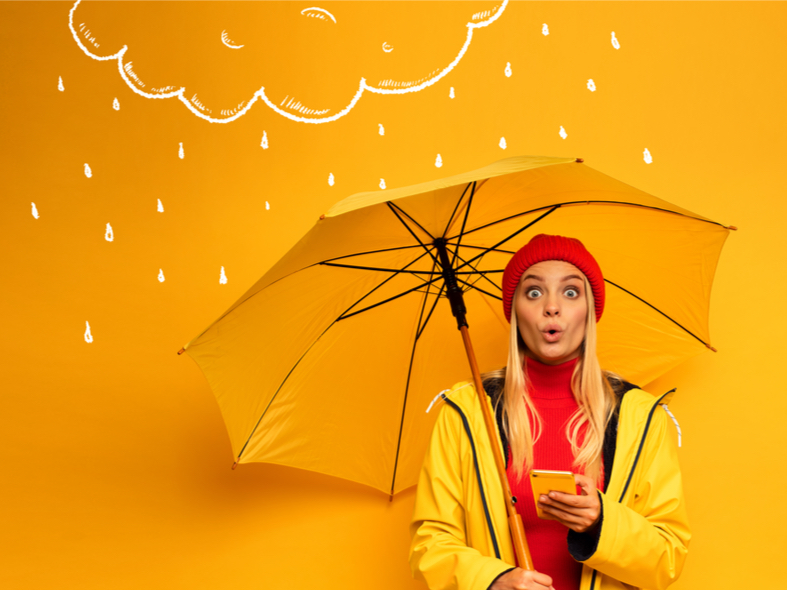 A photo of a woman in a yellow room with a yellow umbrella and yellow phone. She is wearing a red hat and red sweater.