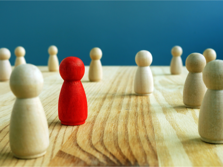 A photo of wooden pegs. One peg is red and the rest are white.