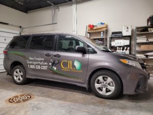 Image of Silver Minivan with the words New Freedom Transportation and CILWW on the side