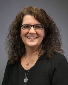 Image of smiling woman with curly hair wearing black.