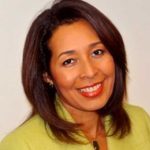 A smiling Latina woman wearing red lipstick and a green blazer