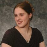 Image of young woman with hair pulled back in a bun looking to her right in a black v necked top.