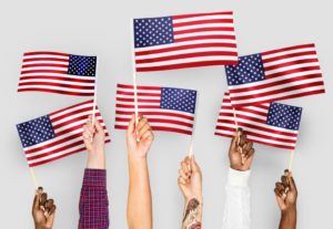 Long Description a series of hands from people of different skin tones one with tattoos holding American Flags