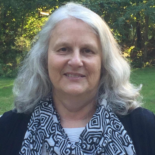 Image of smiling woman with white hair waring an black and white cowl neck sweater and a black cardigan