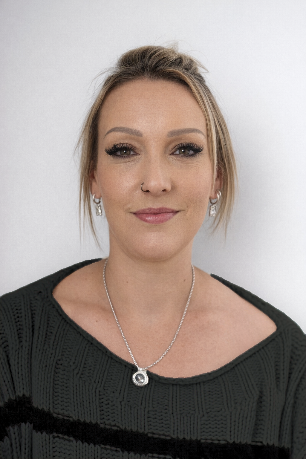 Smiling woman with long blonde hair wearing a blue ribbed buttoned shirt against a light grey background.