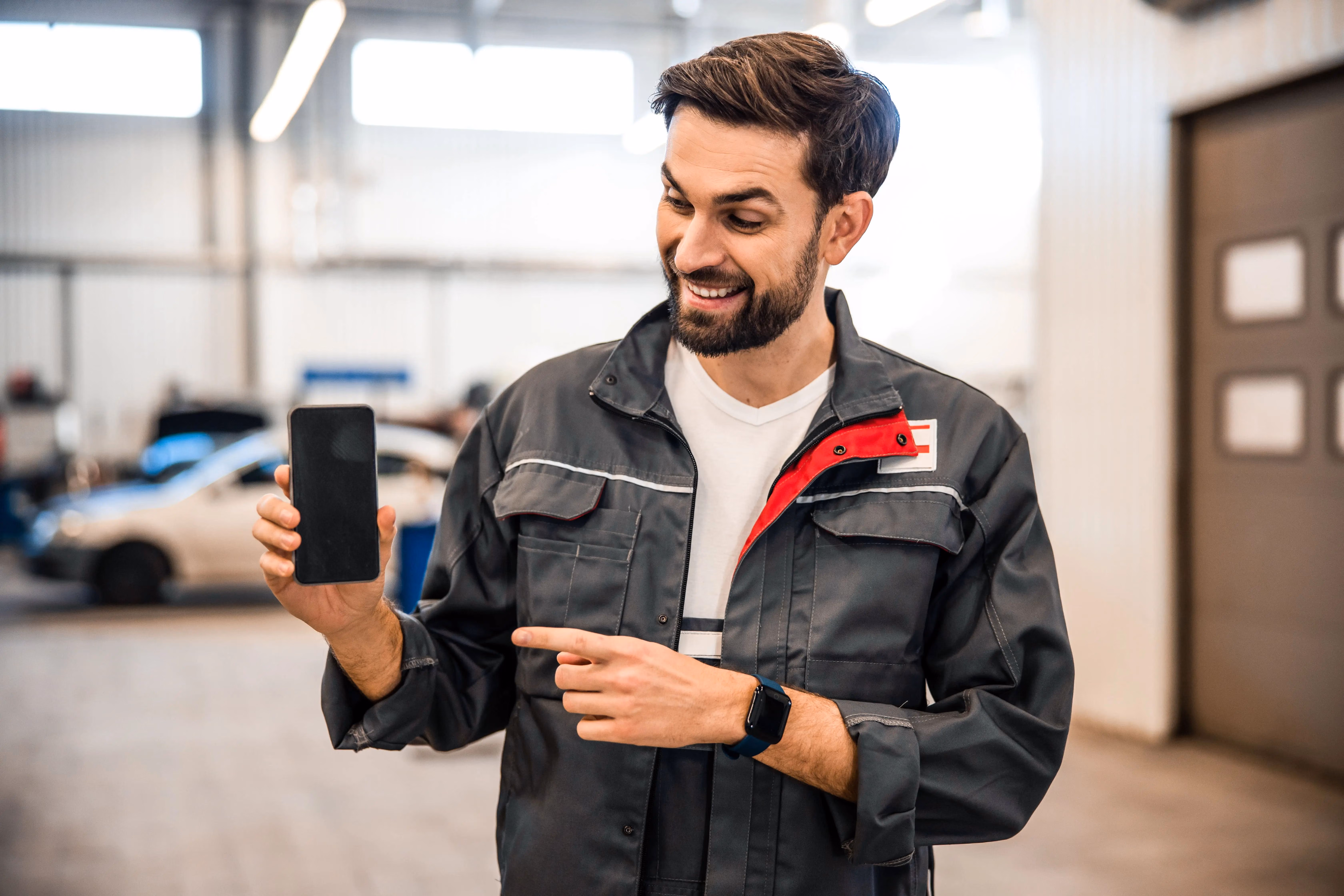 Homem segurando smartphone apontando pra tela do sistema para estacionamento