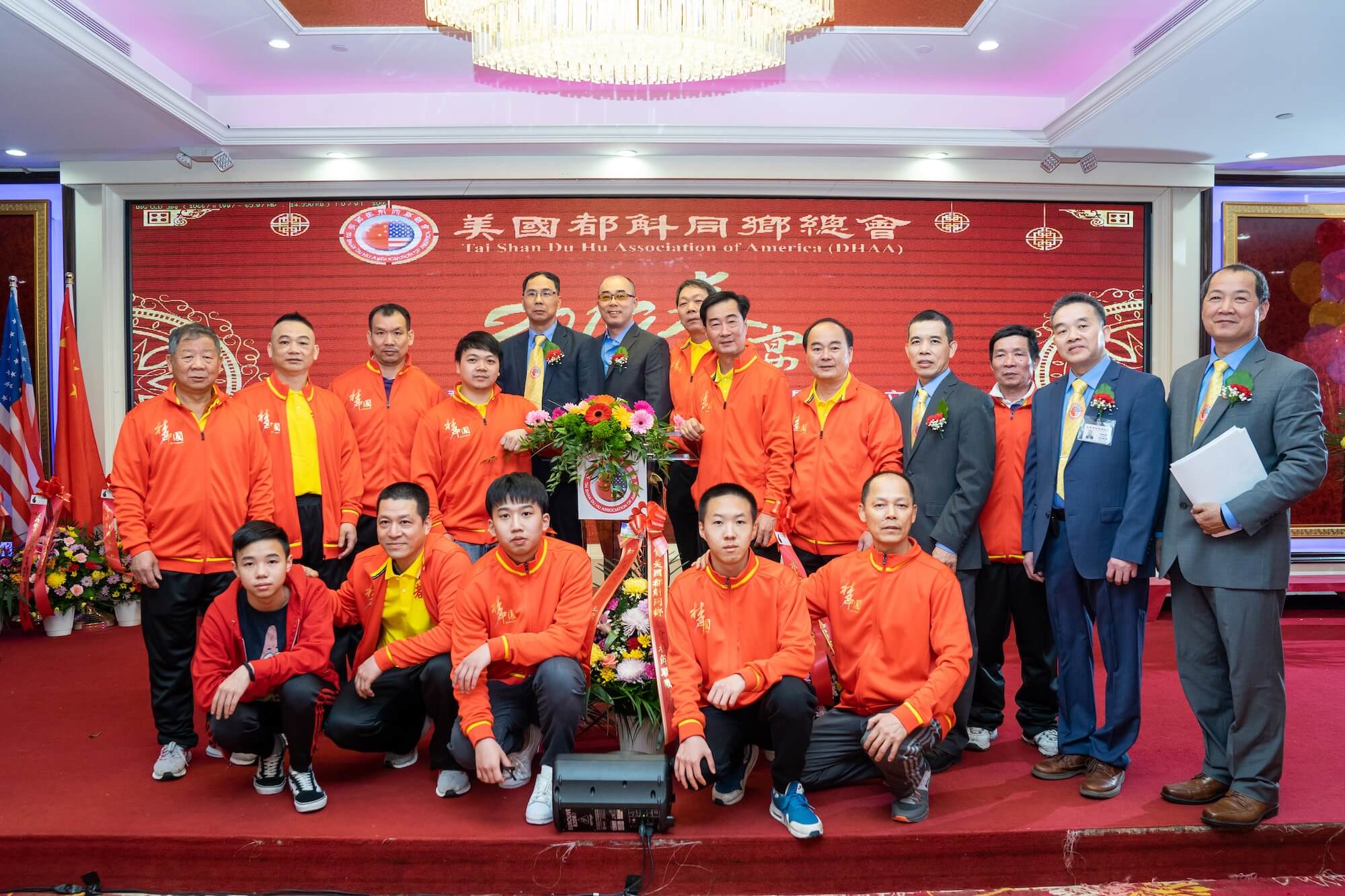 A group of three men collaborate at a wooden table in a modern, open-plan office. Laptops and soda cans are scattered around. The atmosphere is focused and collaborative.