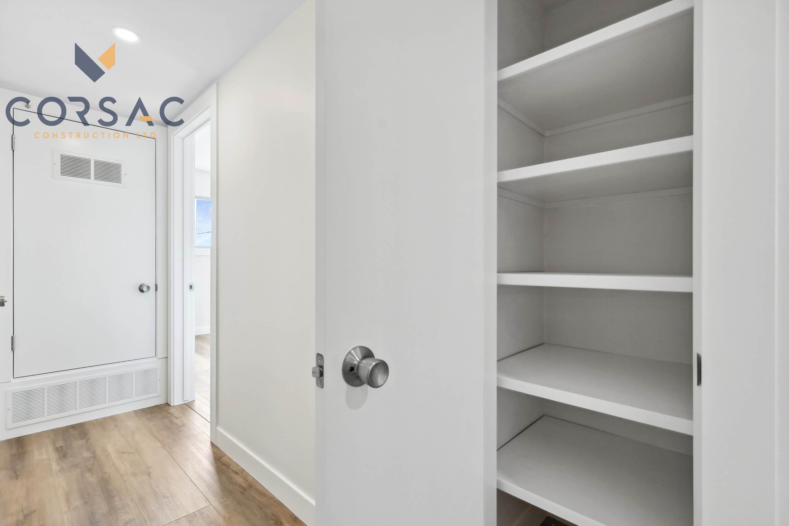 Empty white built-in shelving unit in a hallway with light wood flooring and white walls.