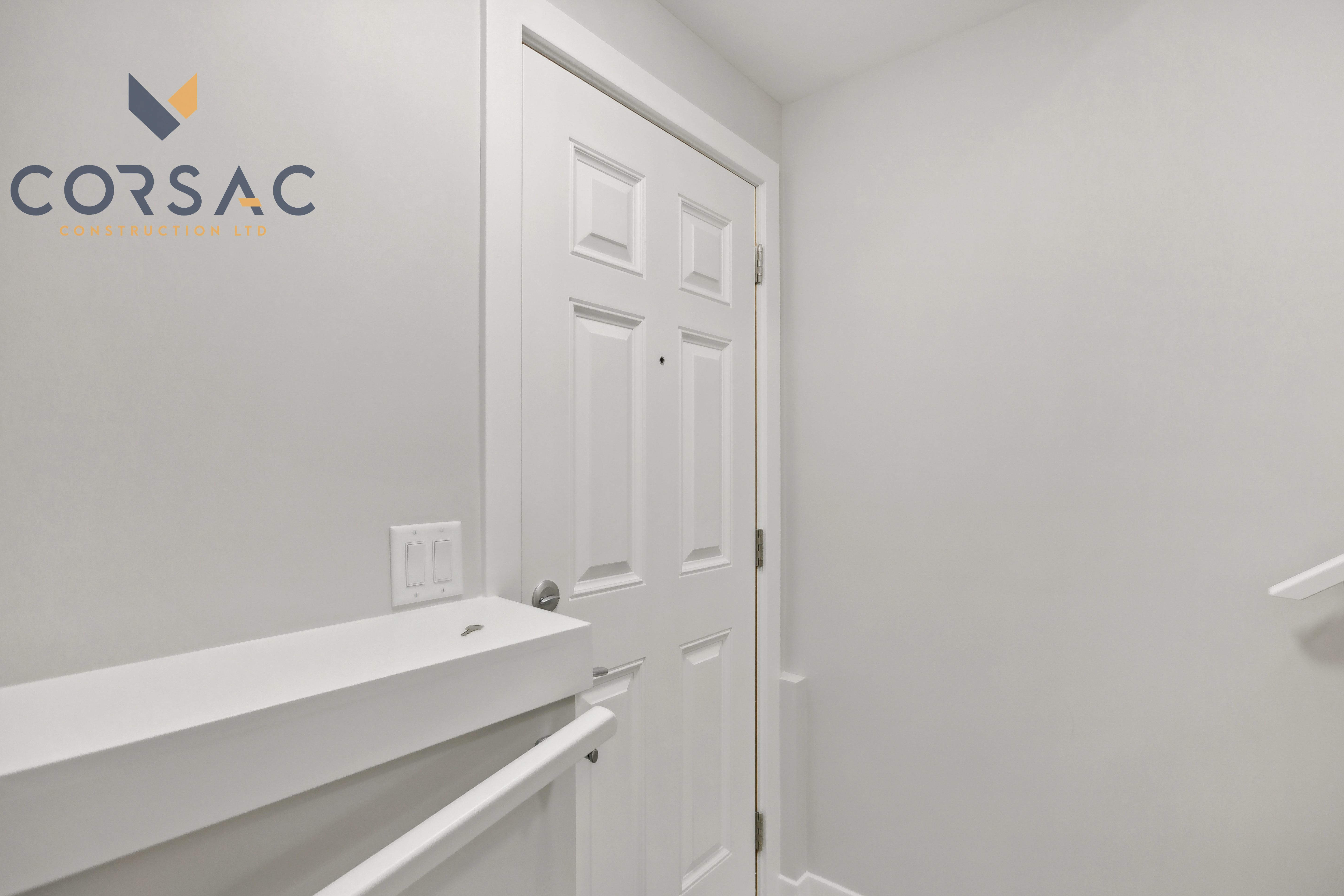 White interior door with silver handle and modern handrails along plain white walls.