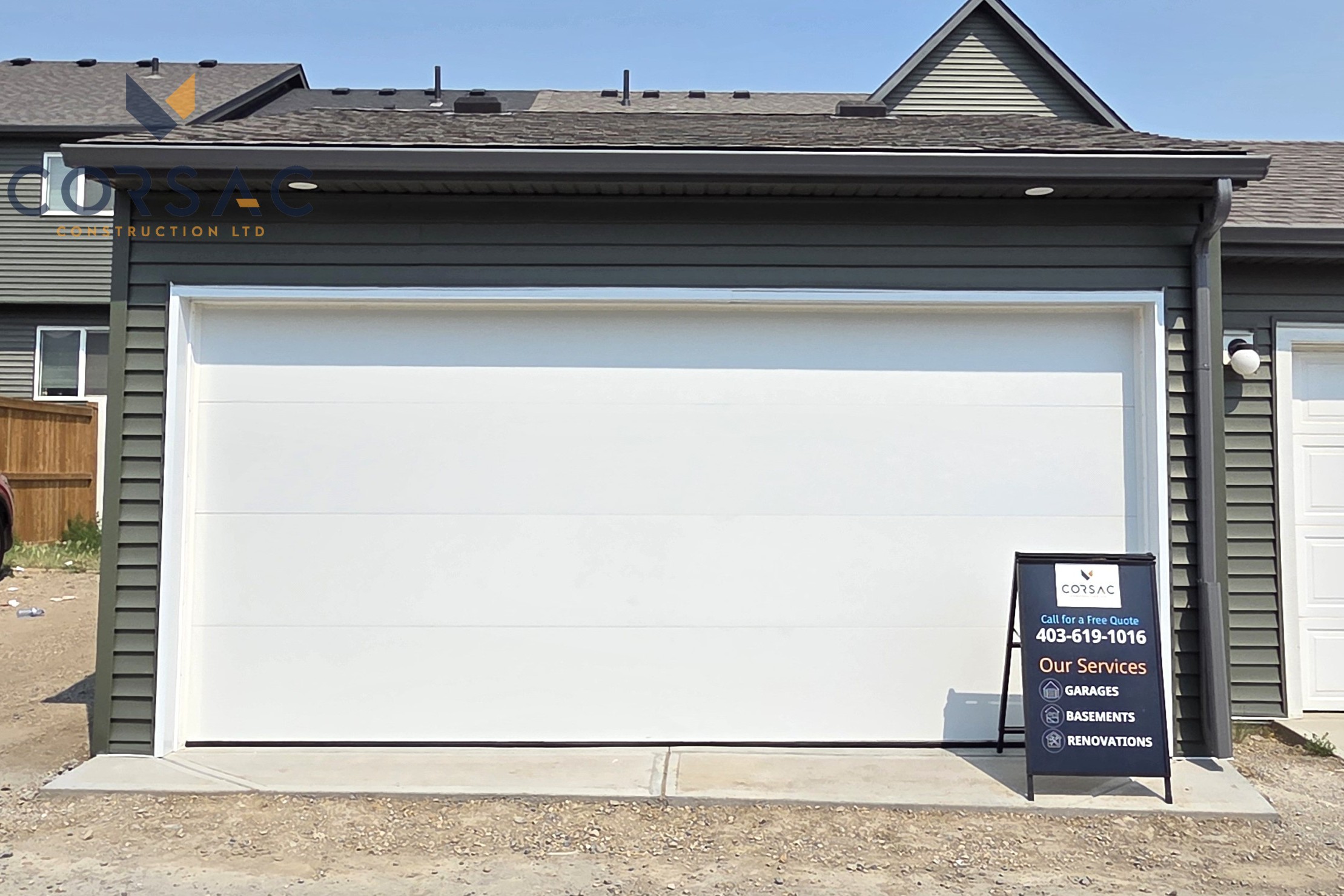 Cream-colored detached garage with a white sectional garage door, brown gutters, outdoor light, and sign on the right side under a blue sky.