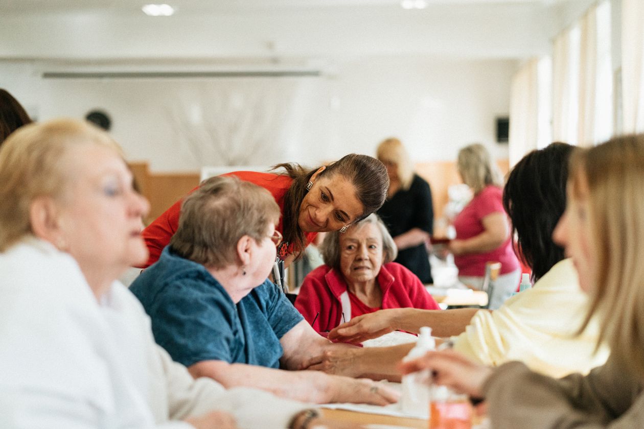 Séjour pour une association de seniors en Bretagne : groupe de seniors souriants réunis autour d'une table avec un accompagnateur.