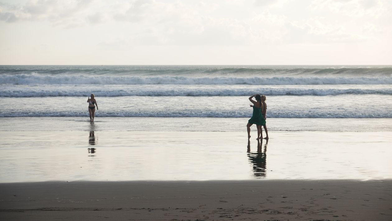 Trois adultes marchant dans l'eau peu profonde en bord de mer, comme lors d'une séance de longe-côte en Bretagne