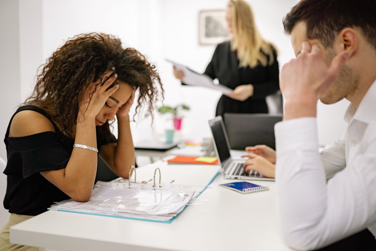 Salariée à son bureau, tête entre les mains, illustrant la double charge du salarié aidant