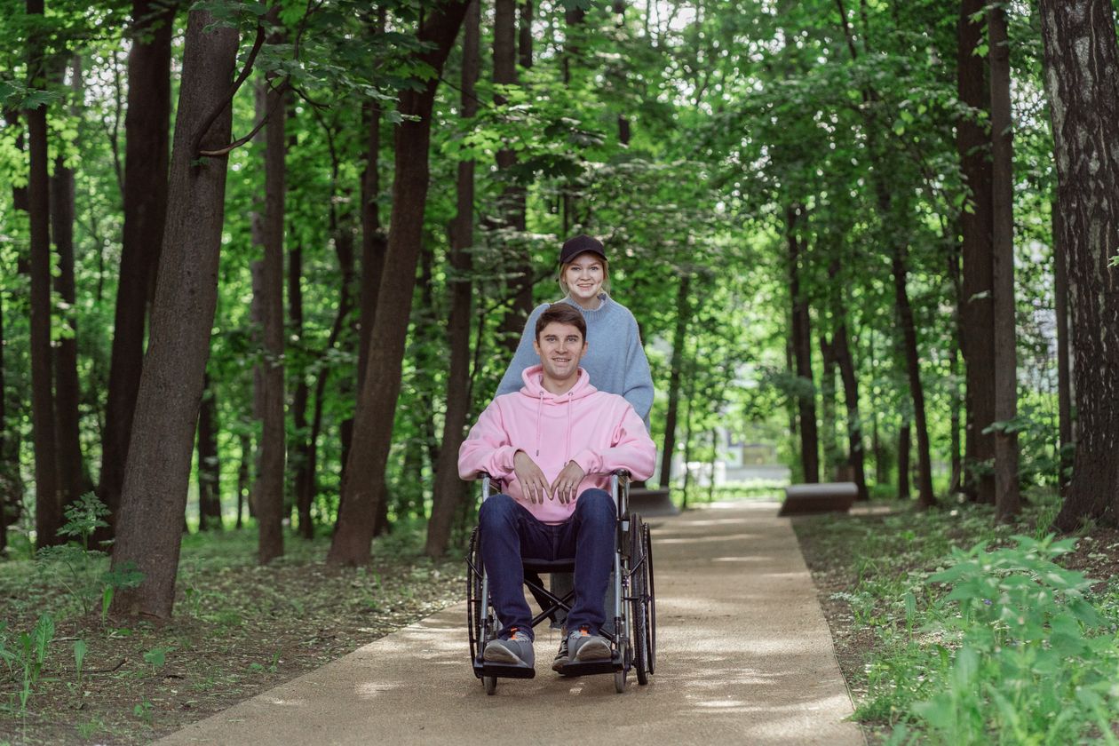 Un couple en promenade sur un chemin ensoleille, l'une des deux personnes en fauteuil roulant