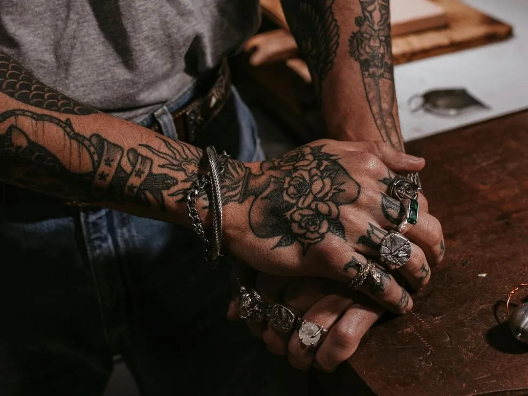 a tattooed person wearing rings