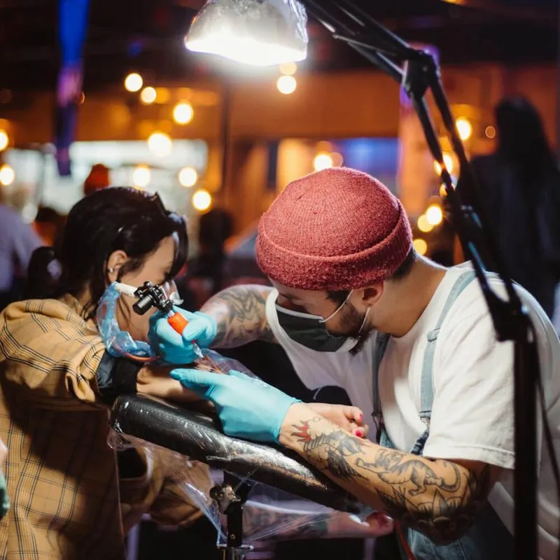 tattooer in hat sitting and working