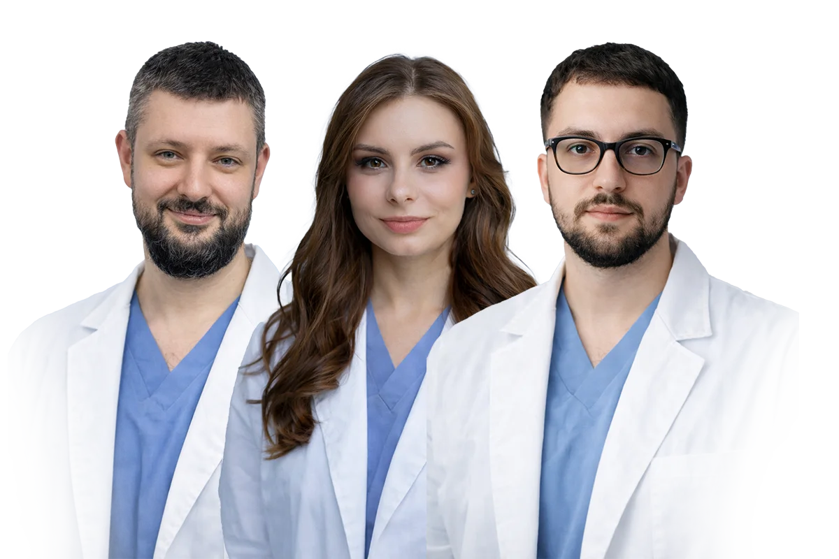 Three medical professionals wearing white coats and blue scrubs standing side by side and looking at the camera.
