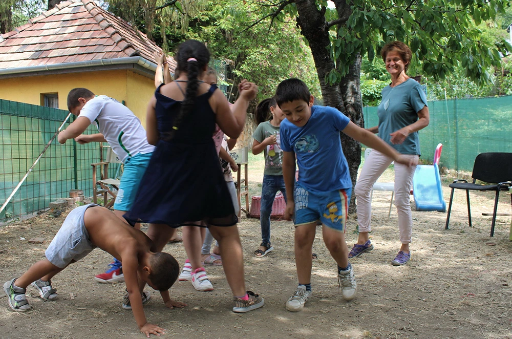Tanodás gyerekek vidáman játszanak egy önkéntessel.