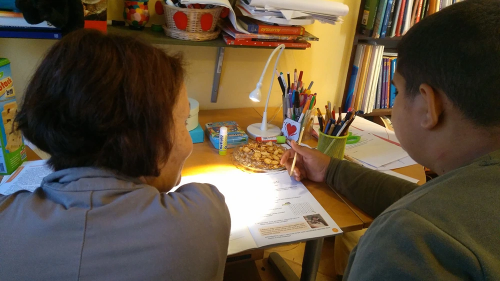 Egy önkéntes közösen tanul egy tanodás gyermekkel.