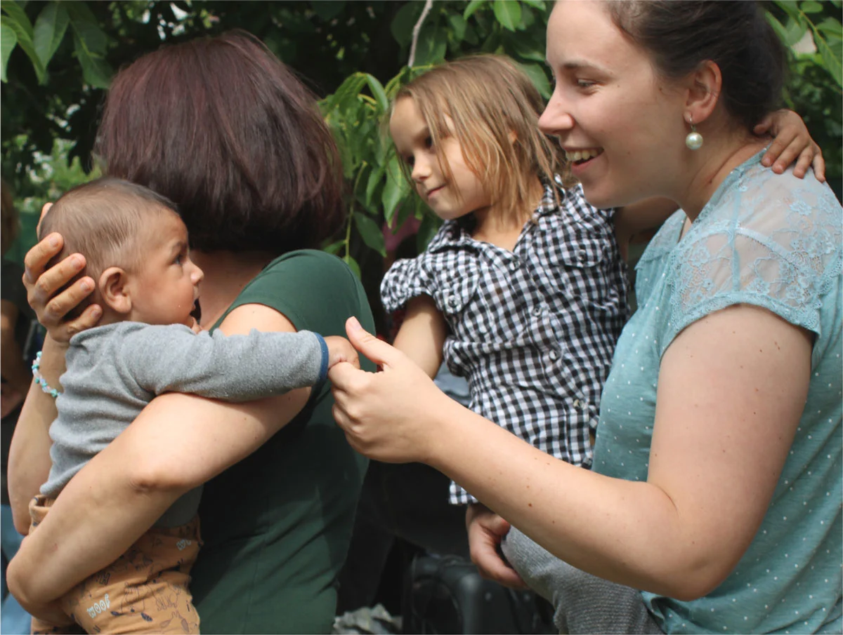 Tanodás mentorok kisebb gyermekeket ölelnek magukhoz.