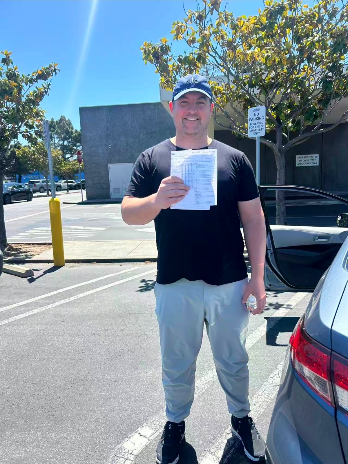 Smiling LLG Driving School student in a navy cap holding DMV papers