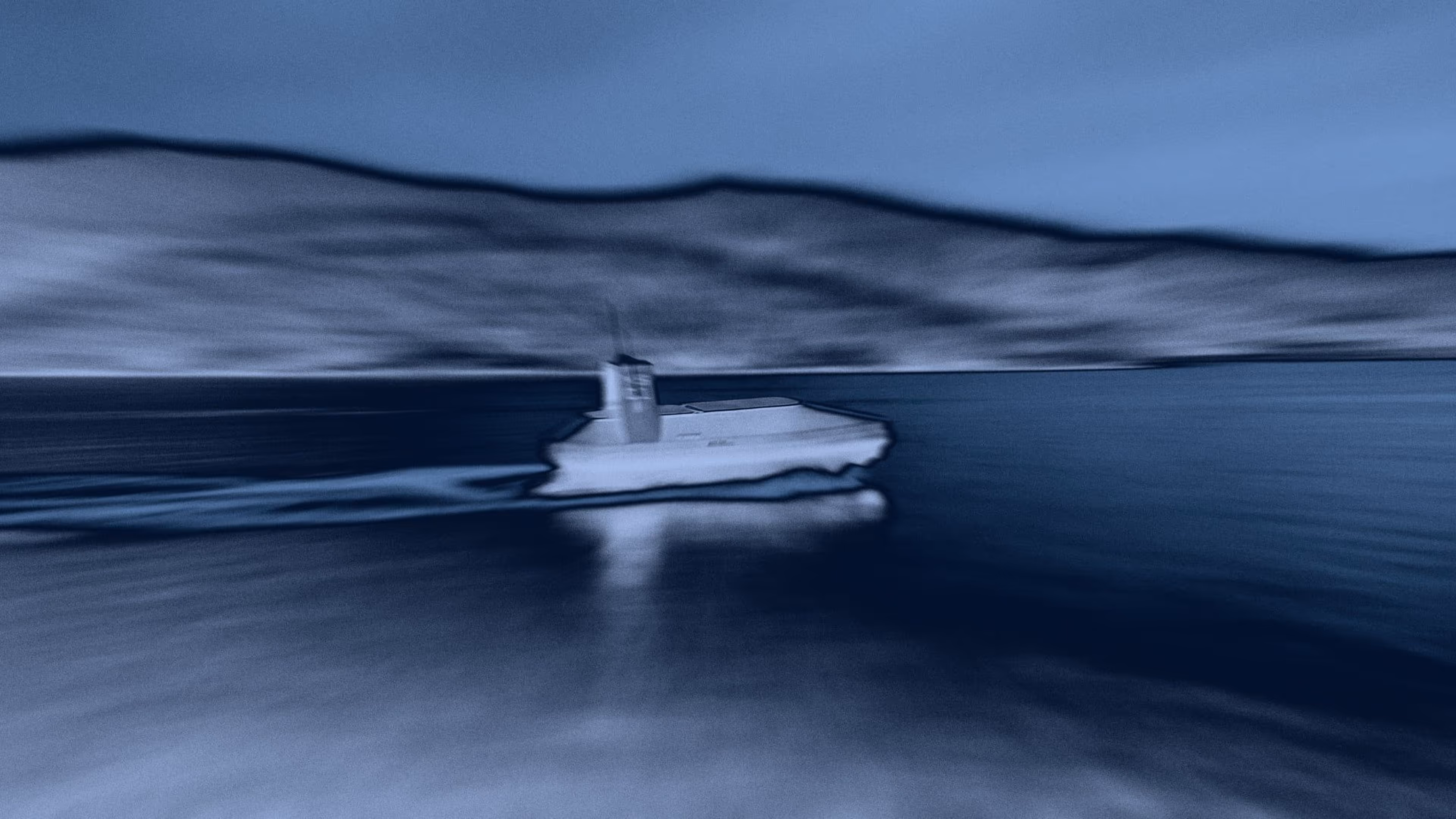 Boat moving quickly on water with blurred effect and mountains in the background.