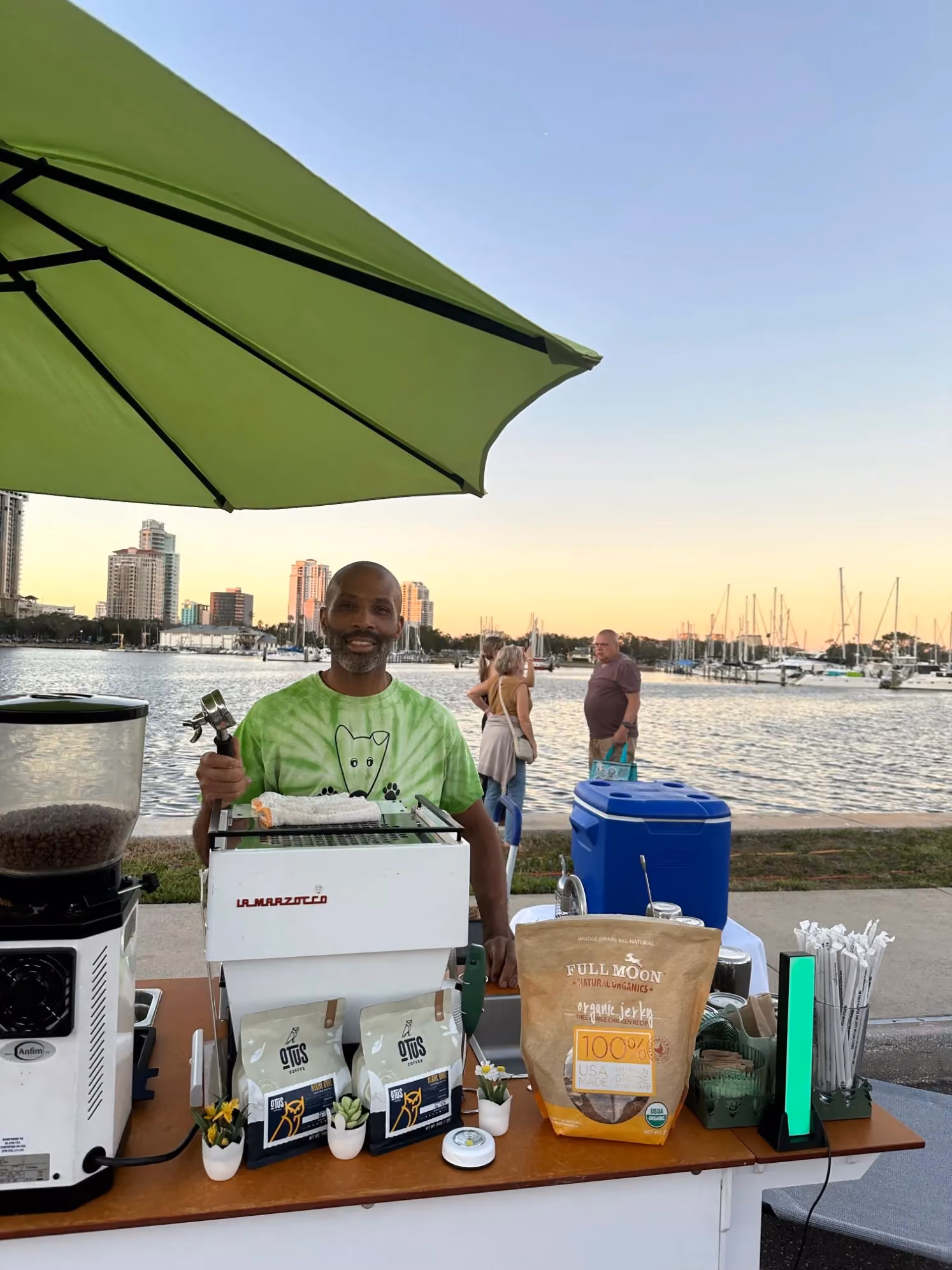 Roy Allen behind the Sage's Playground espresso cart at a waterfront event at sunset in Tampa Bay
