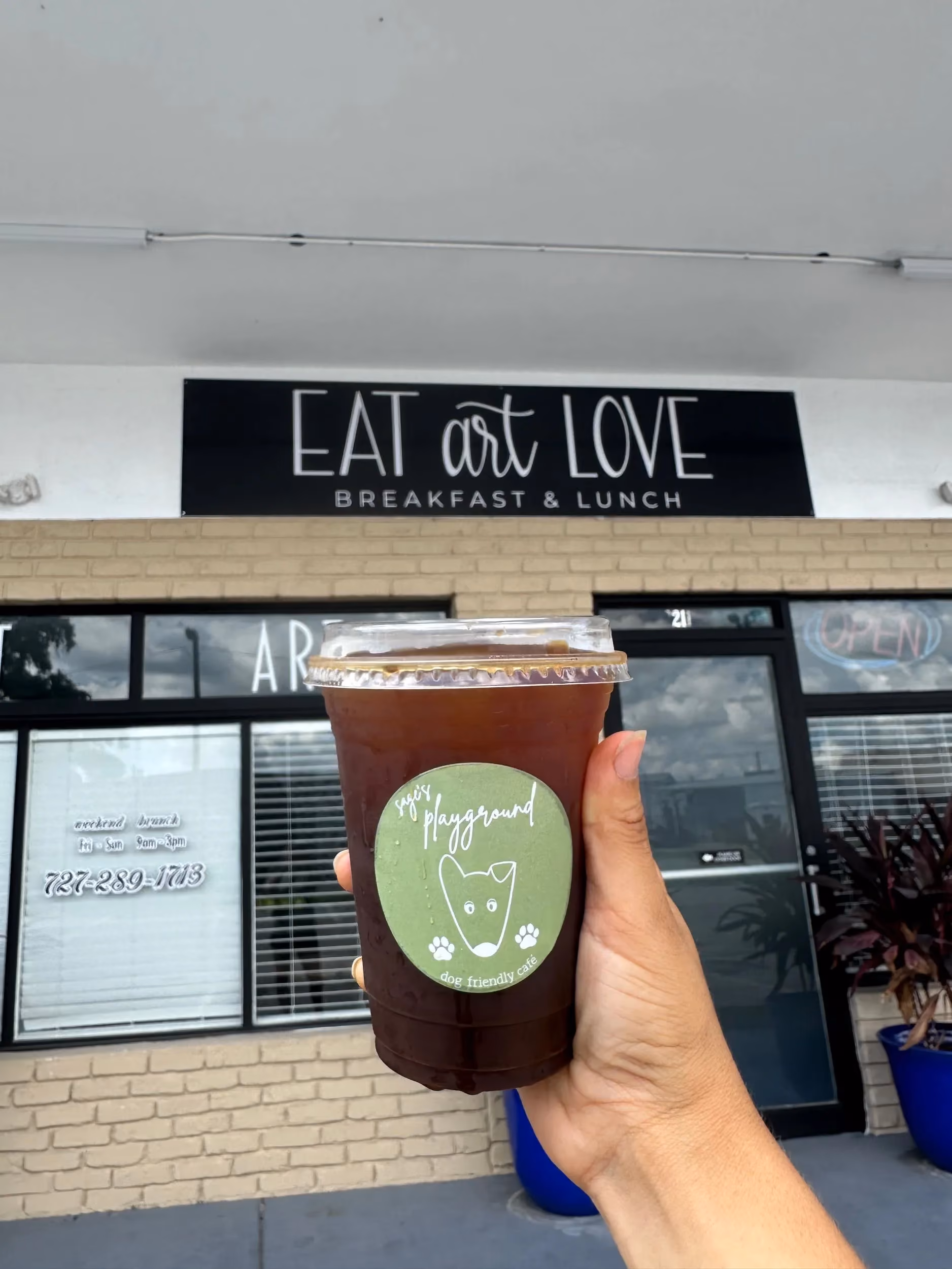 Sage's Playground cold brew held in front of Eat Art Love in St. Petersburg