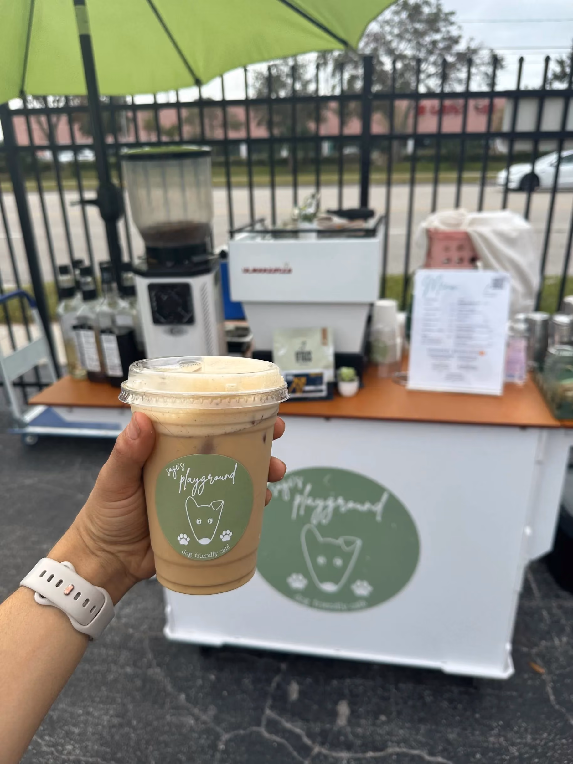 Sage's Playground coffee cup held in front of the cart at an Outdoor Group Fitness event in Tampa Bay
