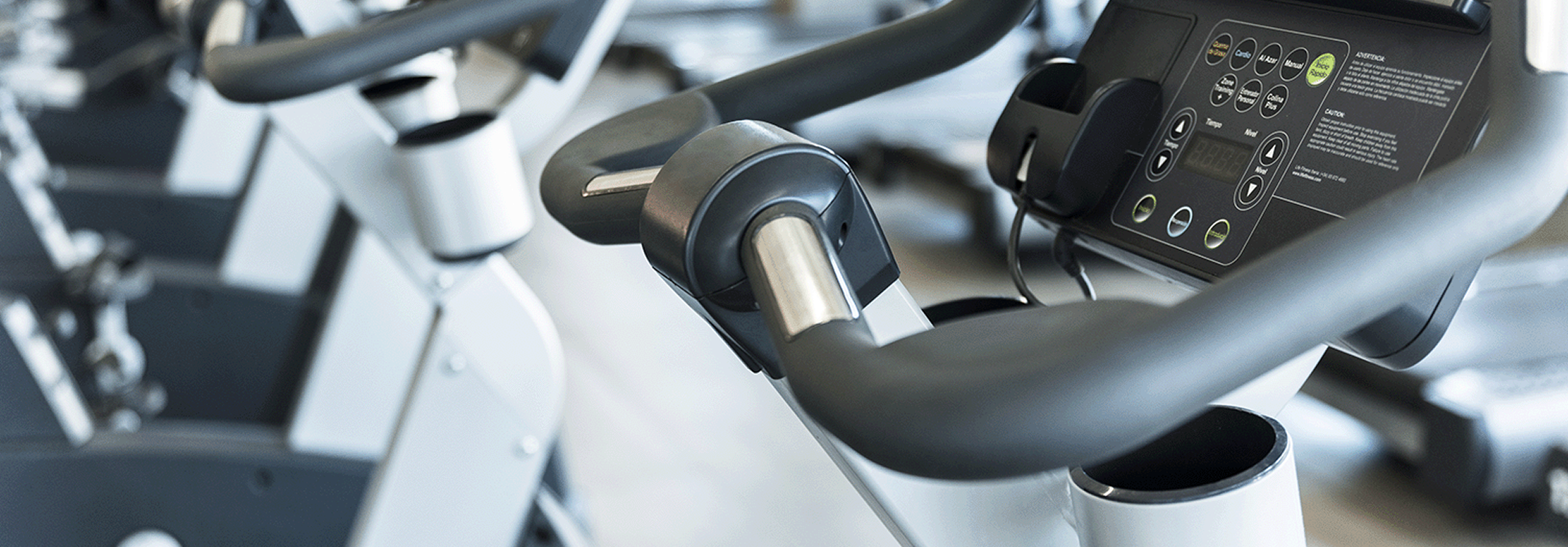 Close-up of the handlebars and digital control panel of a stationary exercise bike in a gym.