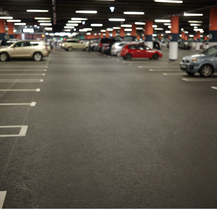 Indoor parking garage with several parked cars and overhead lighting.