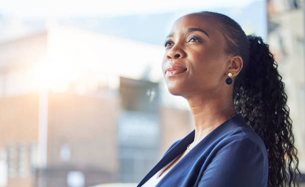 Thoughtful woman with curly hair in a ponytail looking upwards in natural light.