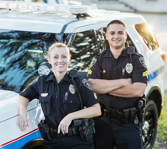 Two police officers standing in front of a patrol vehicle.
