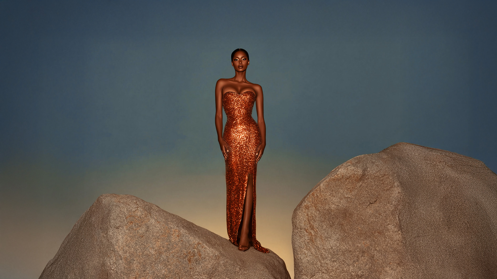 Frau in funkelndem, schulterfreiem, bodenlangem Abendkleid mit Schlitz steht zwischen zwei großen Steinen vor blau-grauem Hintergrund.