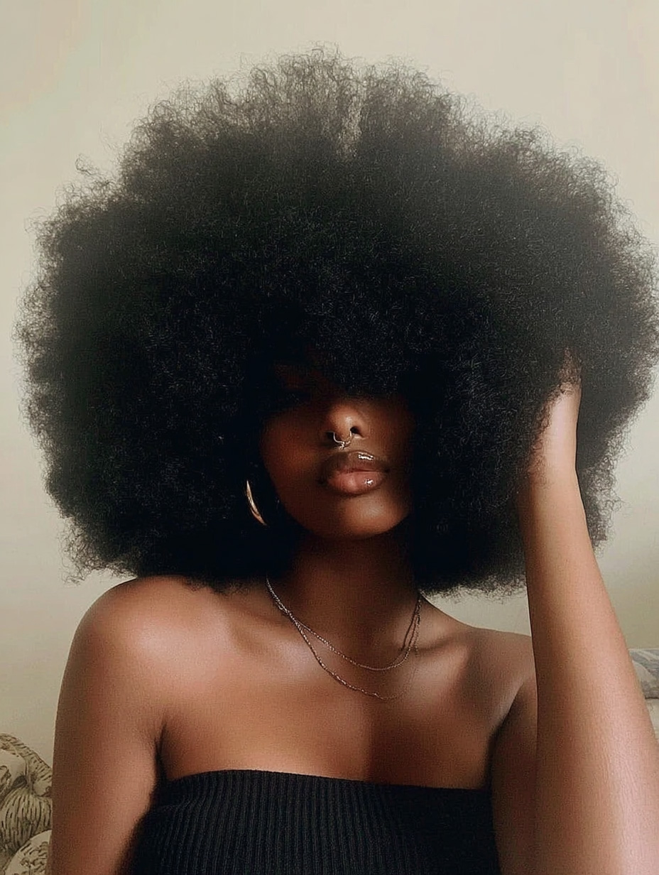 Porträt einer Frau mit großem Afrohaar und Trägerlos-Top.