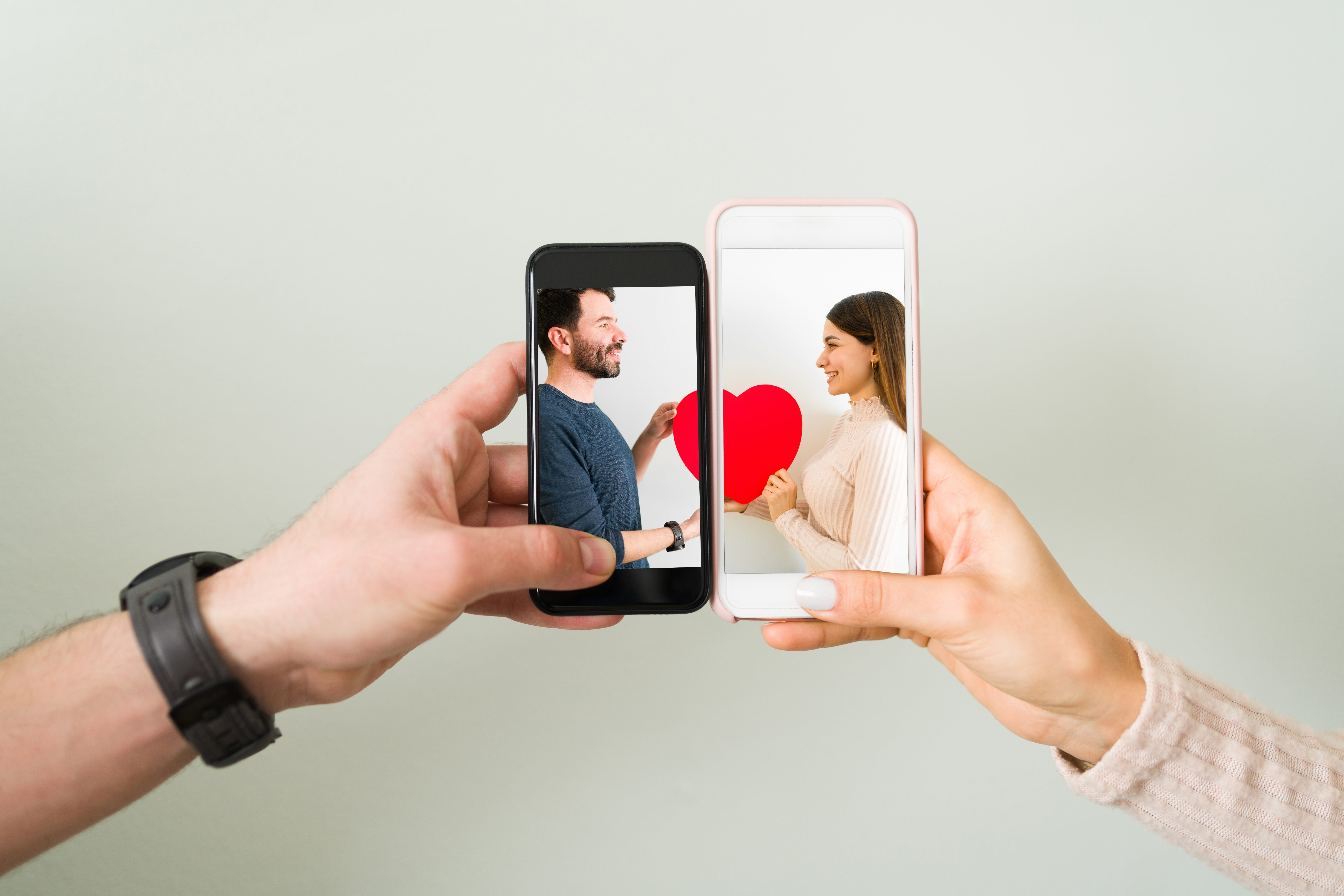 A person holding a smartphone displaying a couple holding a red heart, representing visual brand equity and social intelligence in the dating app industry.