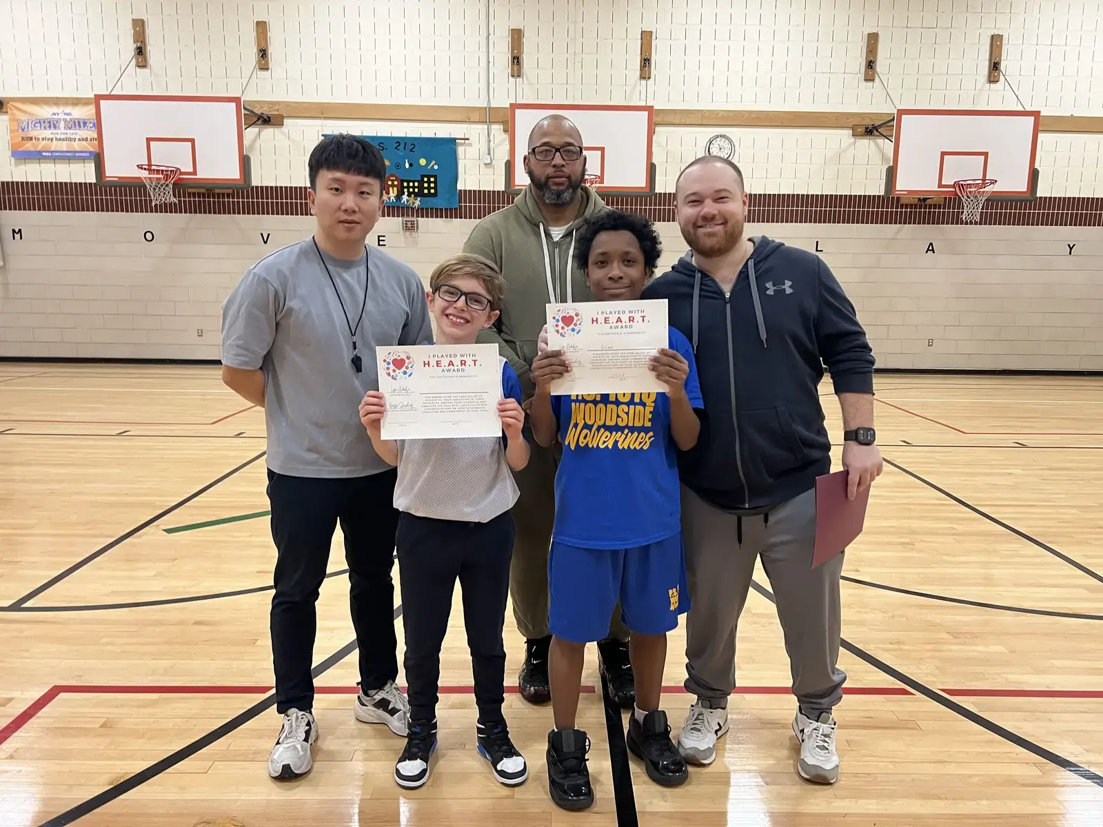 Two students holding HEART Award certificates in school gymnasium