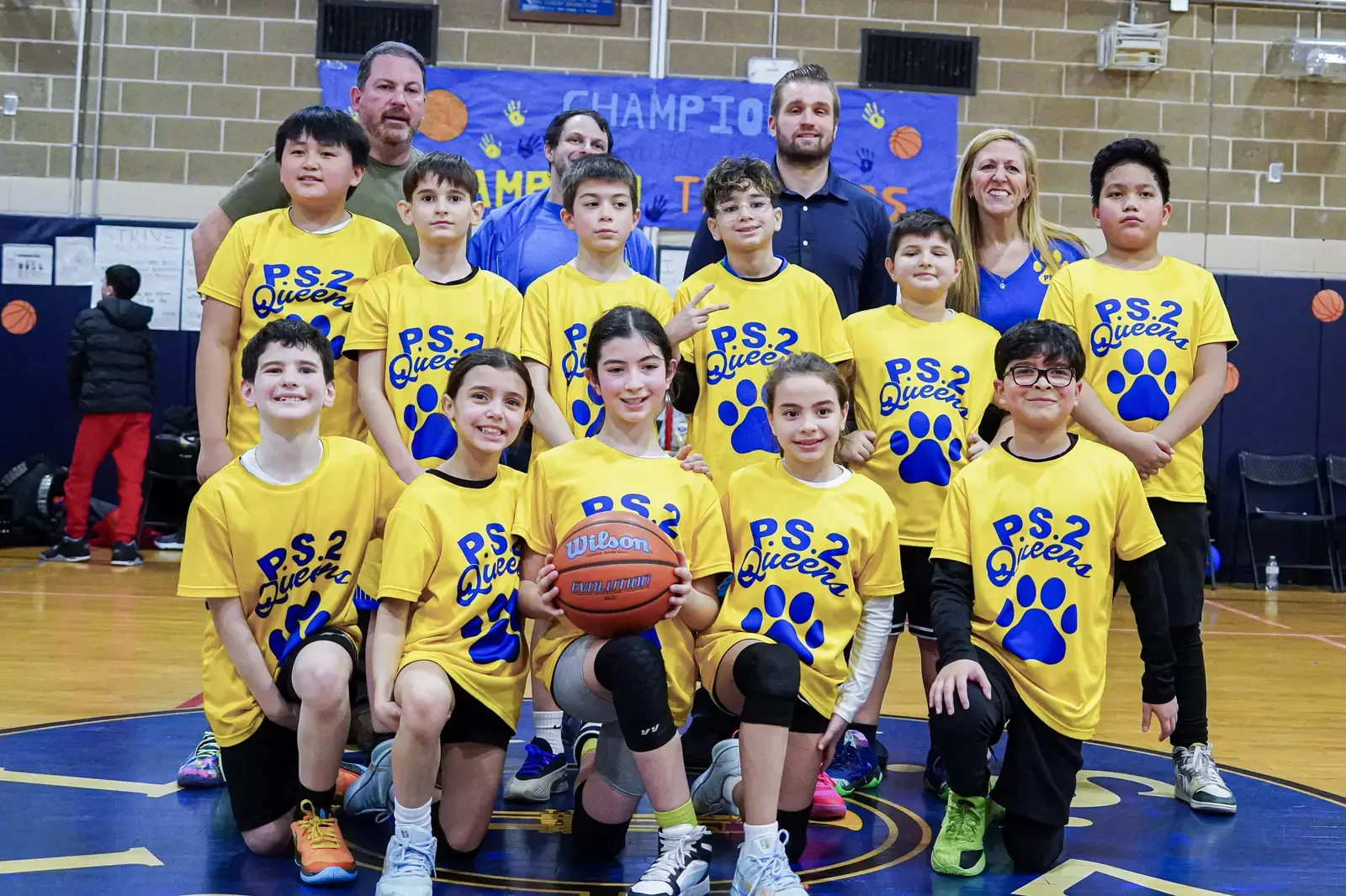 PS 2 Queens elementary basketball team posing with coaches in gymnasium