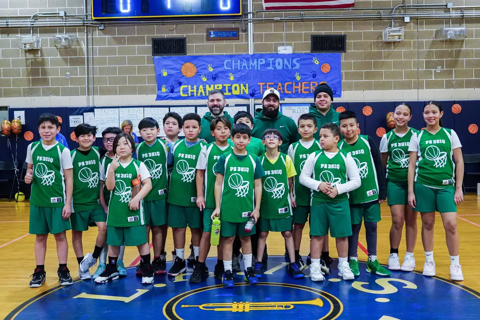 PS 361Q youth basketball team poses with coaches in gym