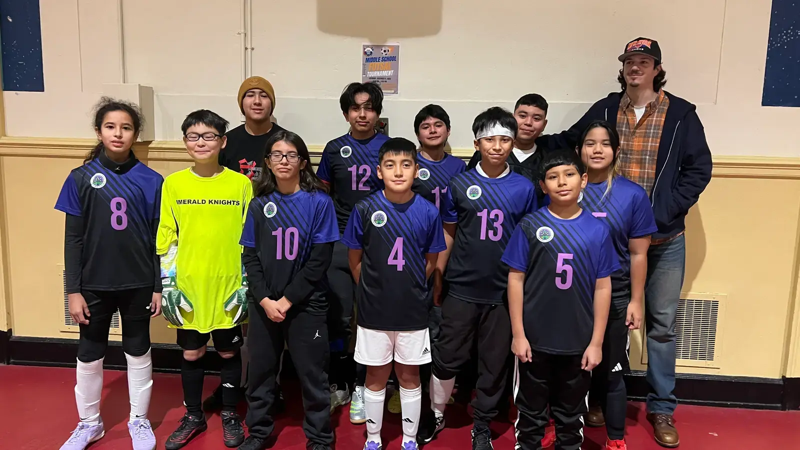 Middle school Emerald Knights soccer team posing indoors with coach