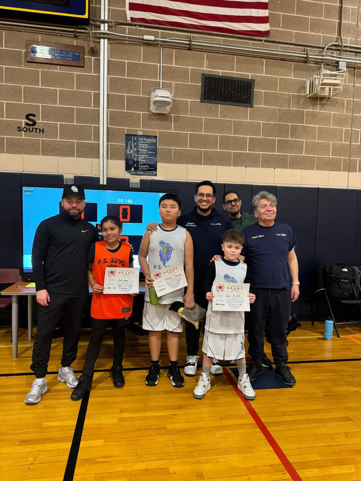 Students and coaches posing with HEART award certificates in school gymnasium