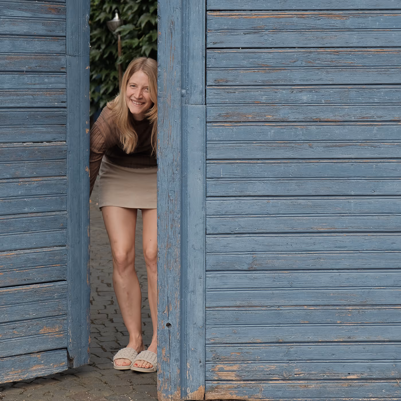 Hand holding a tilted wine glass with white wine and the word RÖDER etched on it against a sunlit background with shadows.