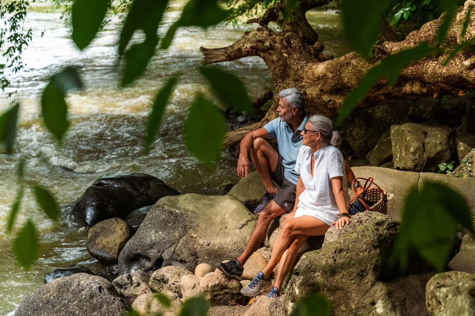 Residents seated beside the river in a wooded setting
