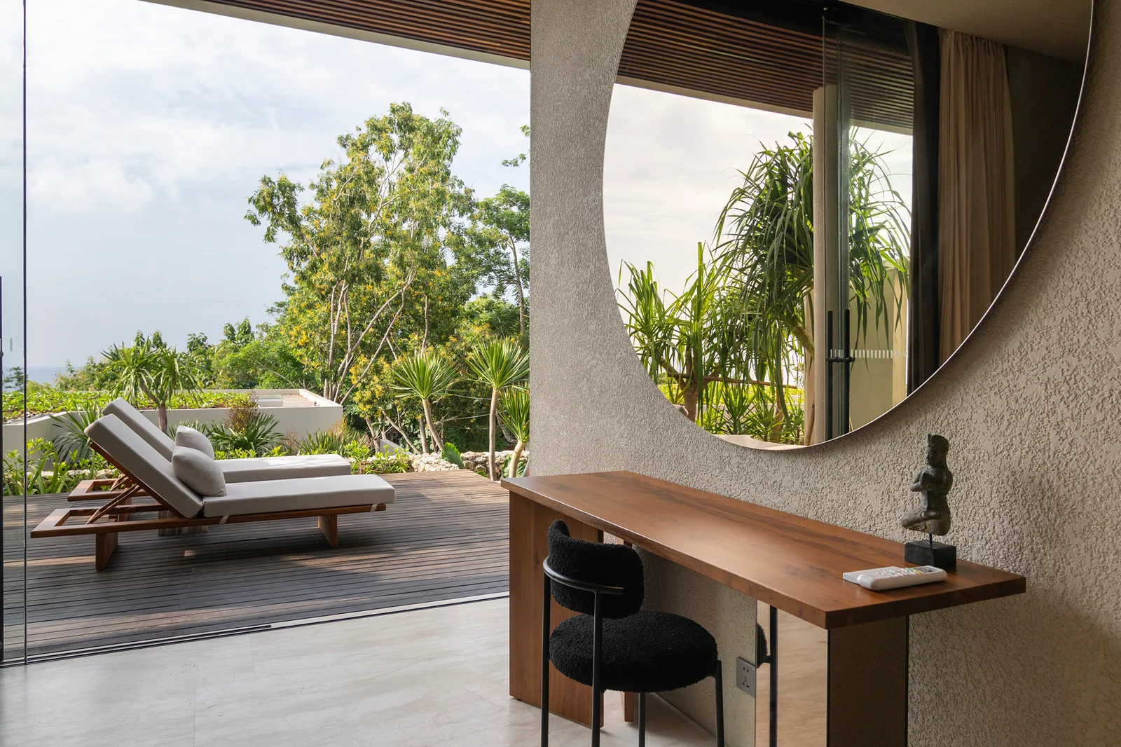 Bedroom vanity with round mirror and terrace lounger outlook