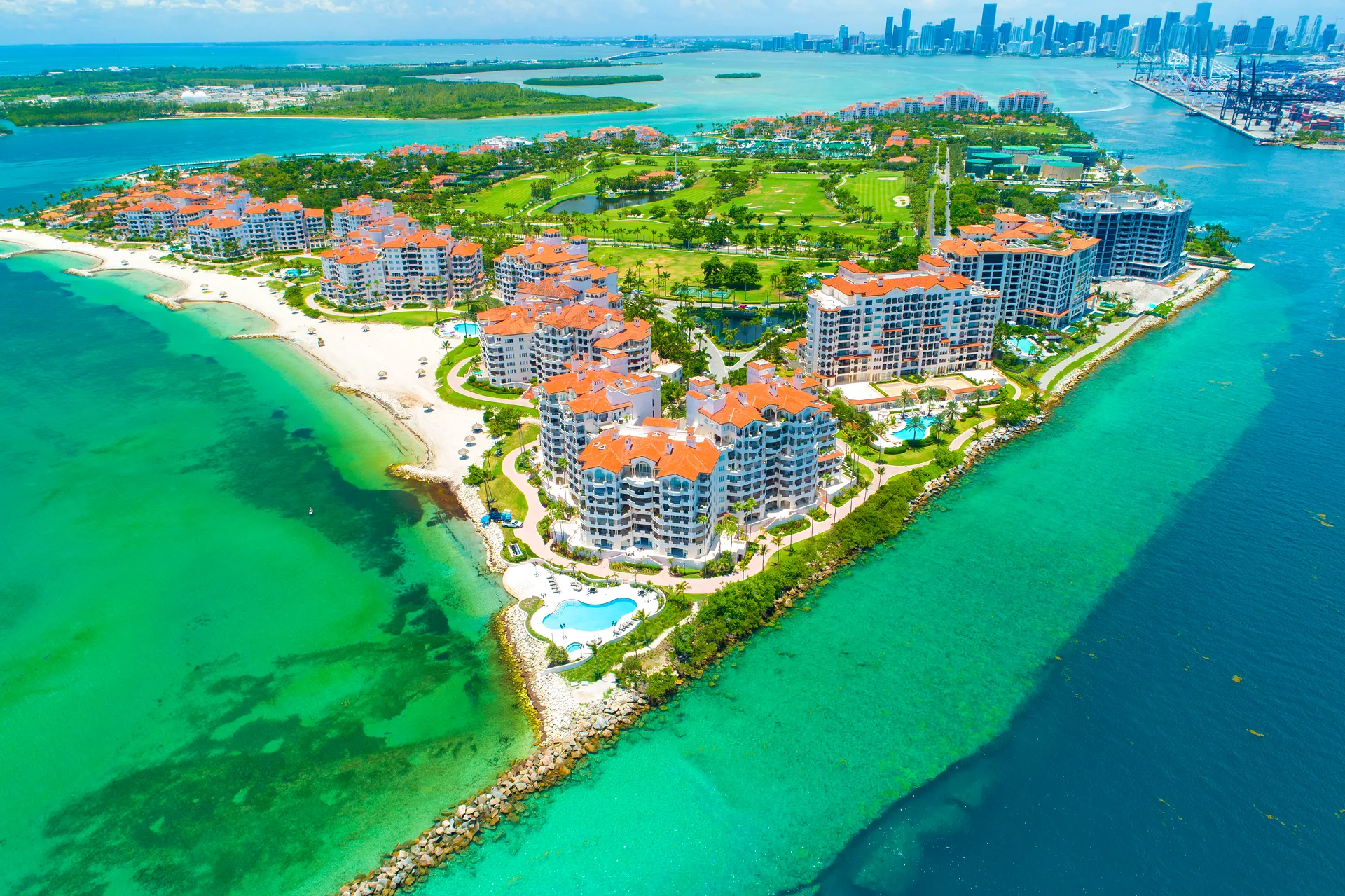 Aerial view of Fisher Island, Miami - Mediterranean-style condominiums, private beach and golf course with the downtown Miami skyline across Government Cut
