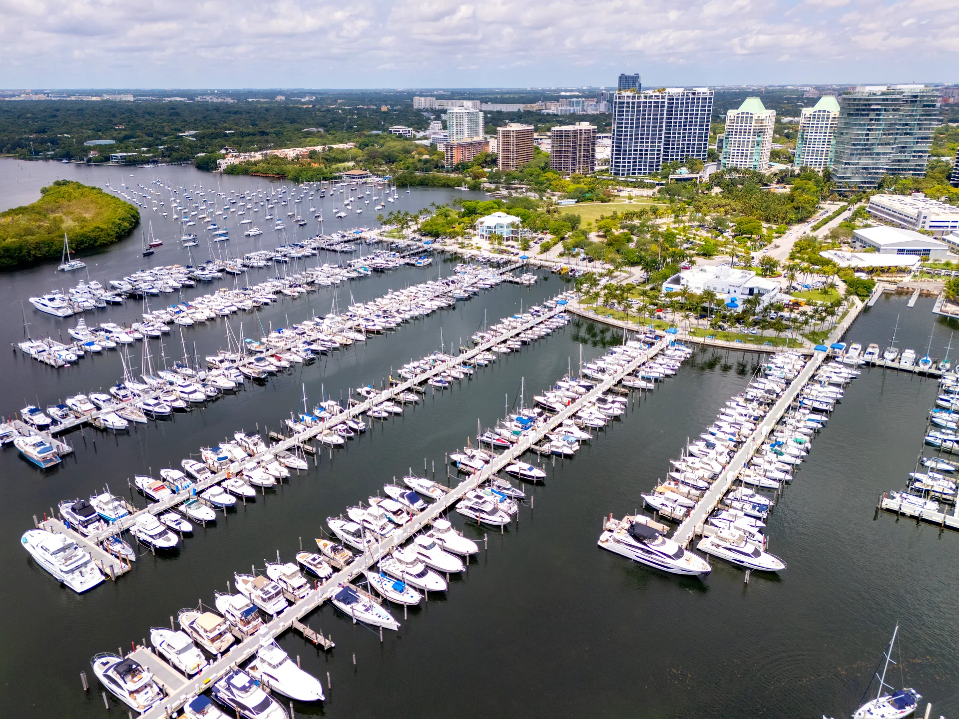 Aerial view of Coconut Grove, Miami - sailboats and yachts at Dinner Key Marina with the Grove's condo towers and tree canopy behind