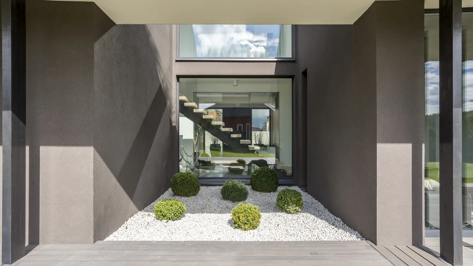 Modern luxury villa entrance with a pebble-and-boxwood garden