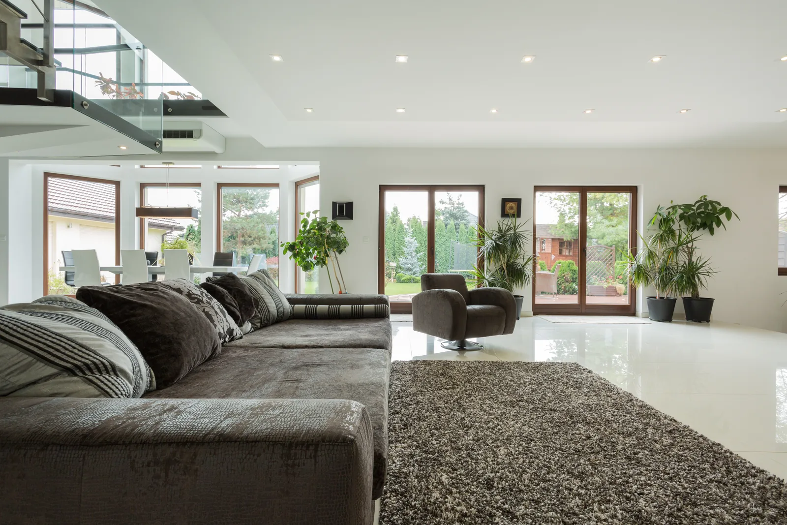 Bright, spacious modern luxury living room with floor-to-ceiling glass and marble floors