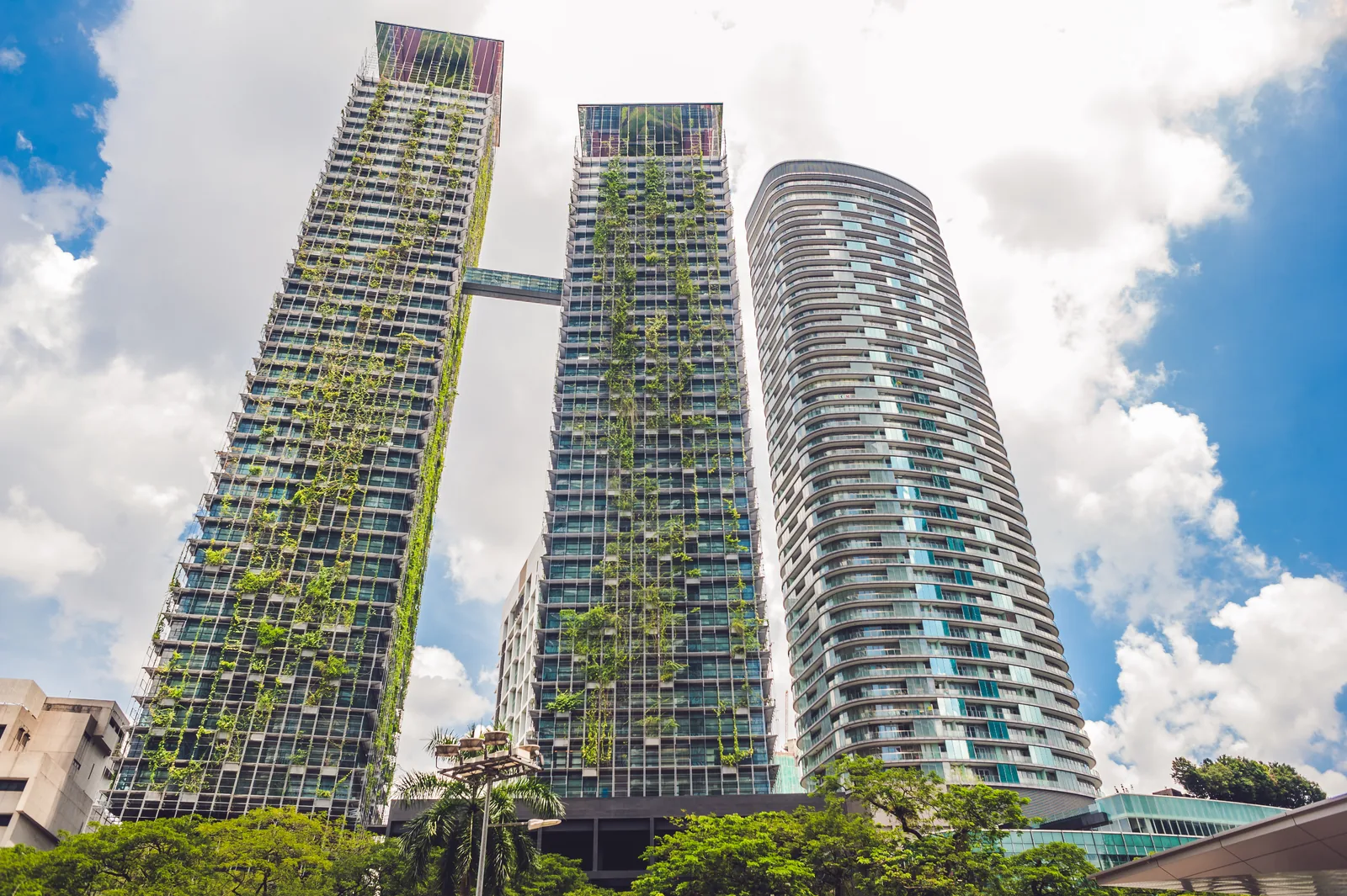Modern high-rise building with lush vertical planting across its glass facade under a clear blue sky