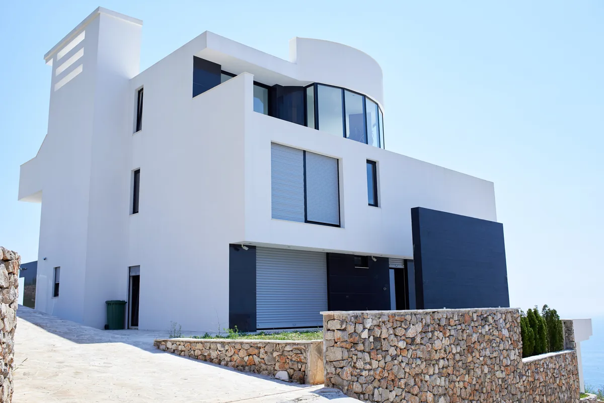 Modern white luxury villa with clean architectural lines under a clear blue sky